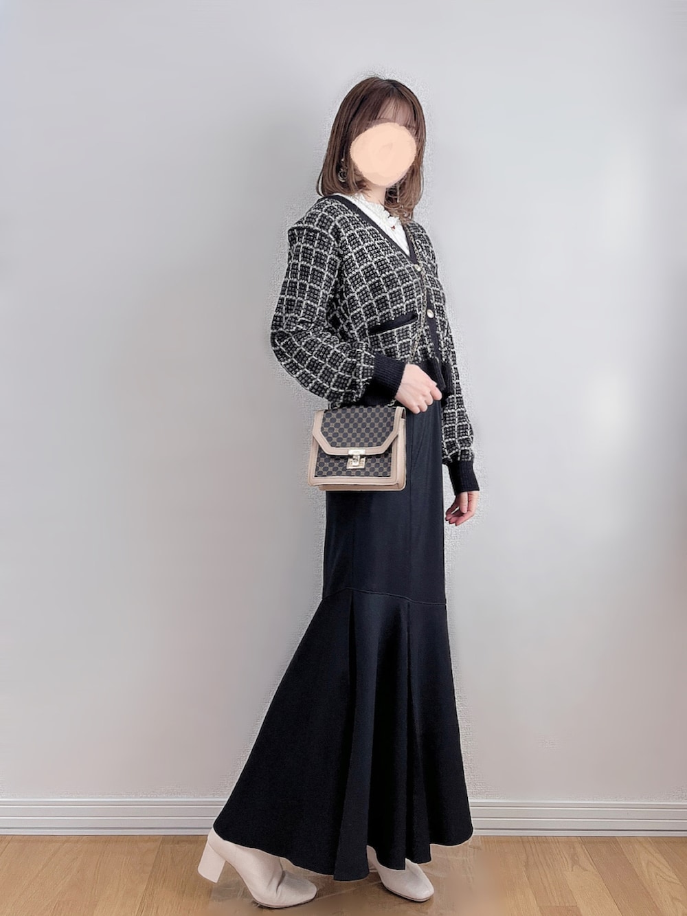 ブラック系のカーディガン/ボレロ、ホワイト系のTシャツ/カットソー、ブラック系のスカートを着用したレディースの冬コーディネートの2枚目の写真