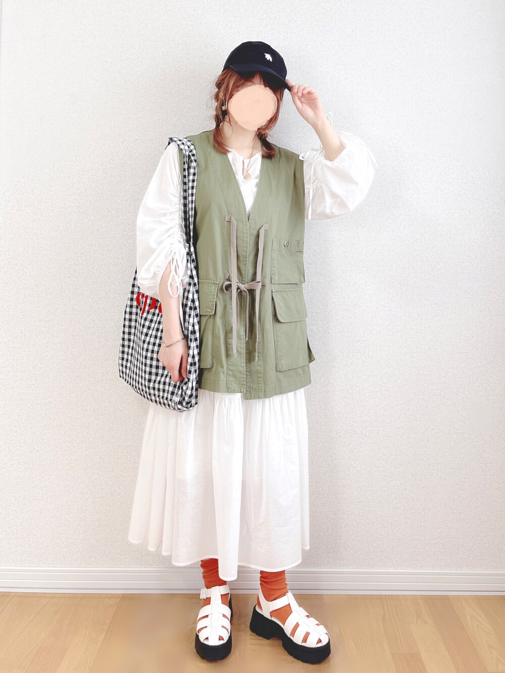 グリーン系のベスト、ホワイト系のワンピース、ブラック系のトートバッグを着用したレディースの夏コーディネートの3枚目の写真