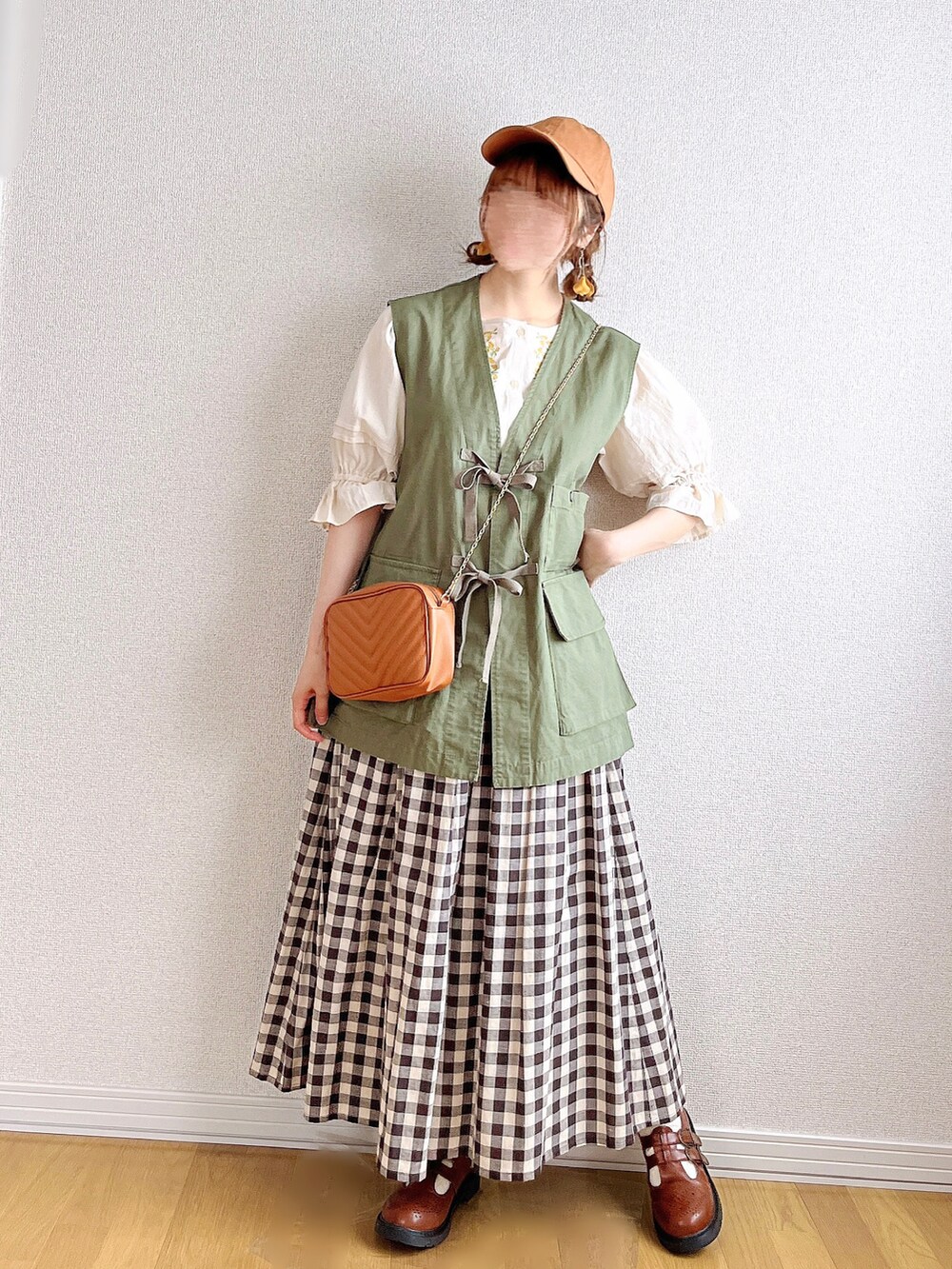 グリーン系のベスト、ホワイト系のシャツ/ブラウス、ブラック系のスカートを着用したレディースの夏コーディネートの2枚目の写真