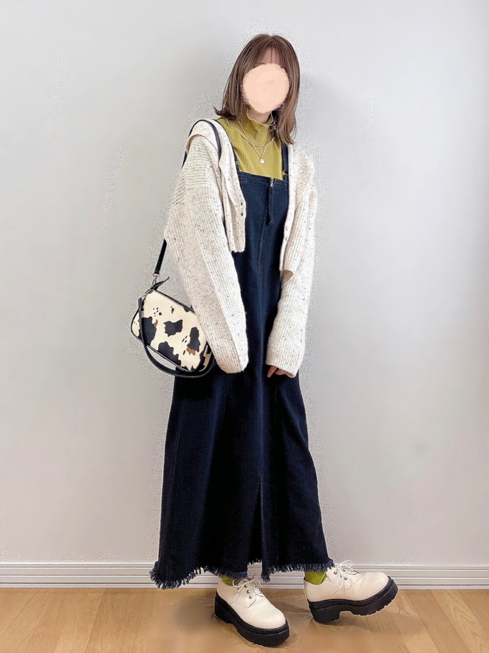 ブラック系のジャンパースカート、ホワイト系のカーディガン/ボレロ、イエロー系のTシャツ/カットソーを着用したレディースの秋コーディネートの5枚目の写真