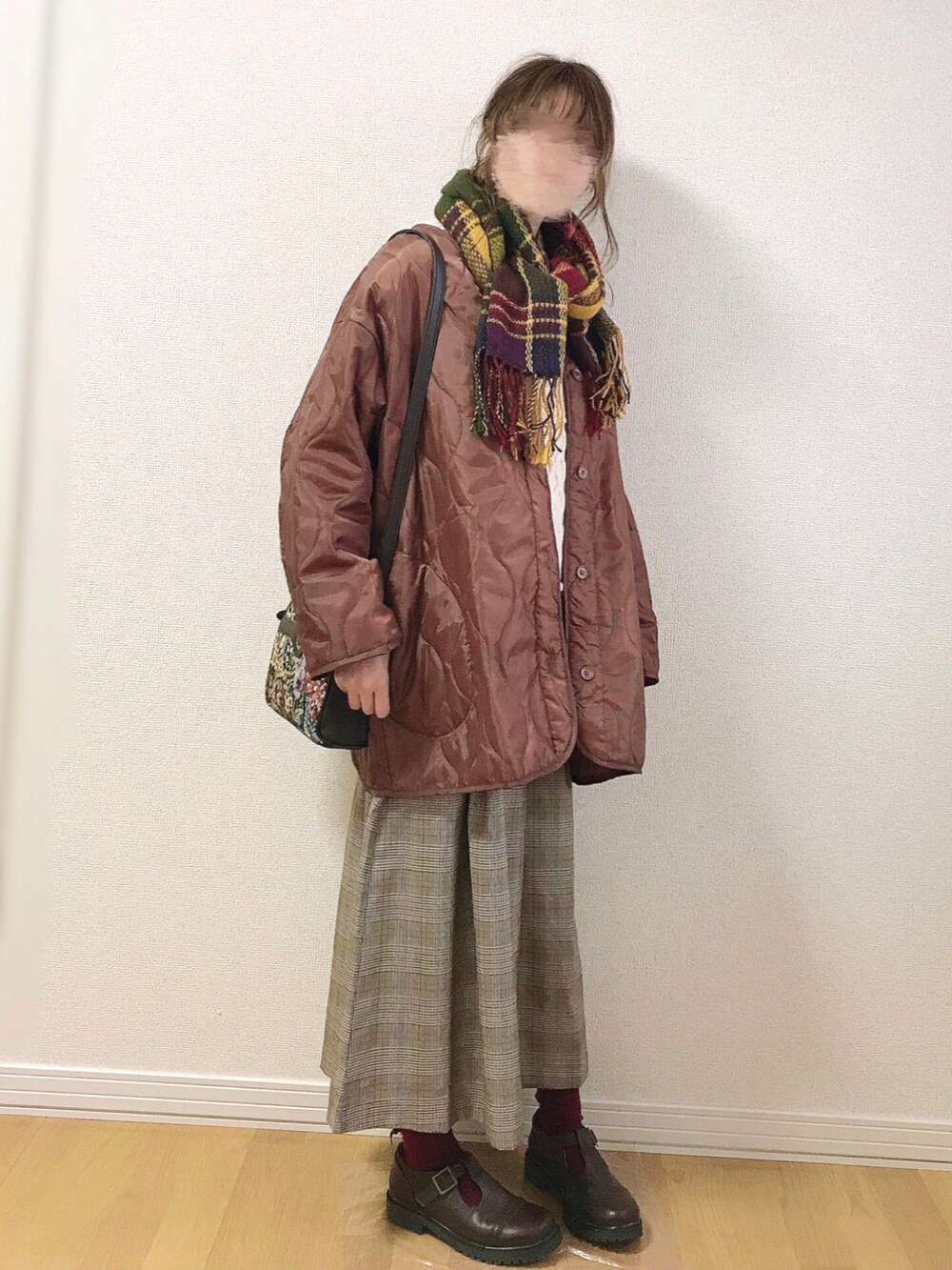 ブラウン系のノーカラーコート、ベージュ系のベスト、ブラウン系のスカートを着用したレディースの冬コーディネートの4枚目の写真