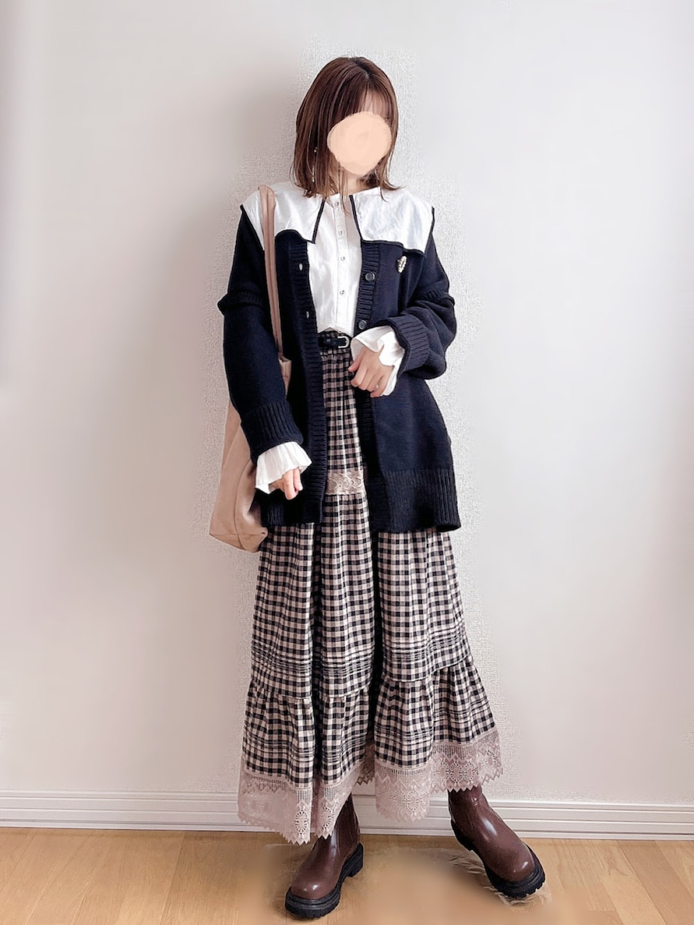 ブラック系のニット/セーター、ブラウン系のブーツ、ベージュ系のトートバッグを着用したレディースの冬コーディネートの3枚目の写真