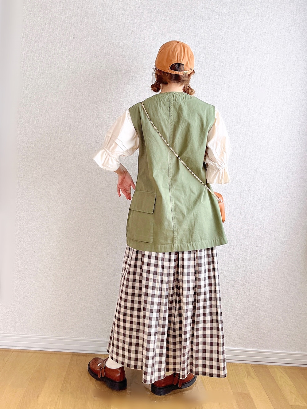 グリーン系のベスト、ホワイト系のシャツ/ブラウス、ブラック系のスカートを着用したレディースの夏コーディネートの4枚目の写真