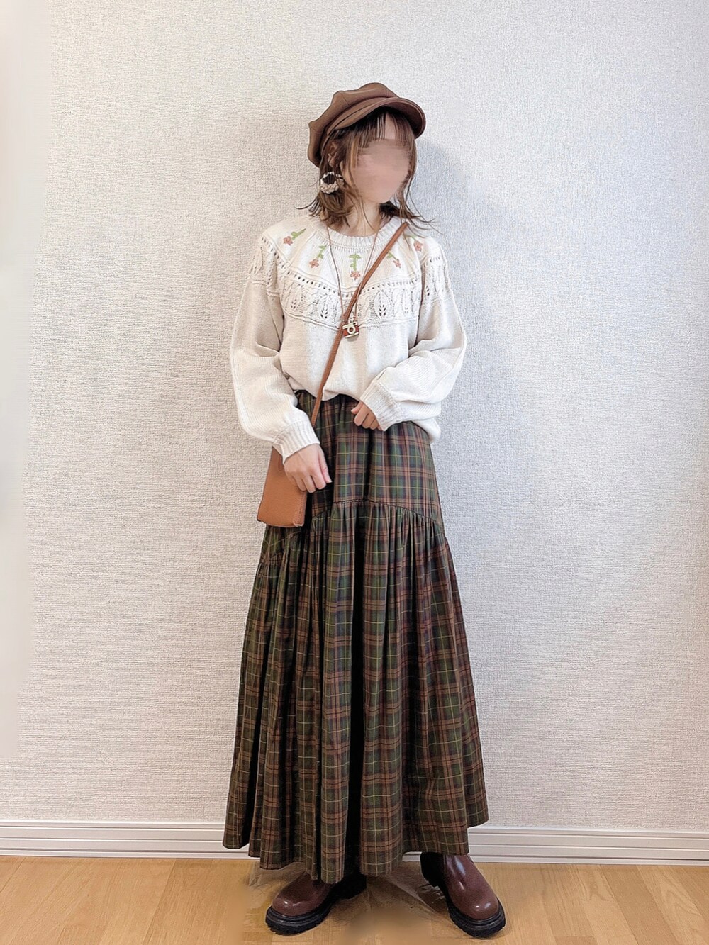 ホワイト系のニット/セーター、ベージュ系のベスト、ブラウン系のスカートを着用したレディースの秋コーディネートの3枚目の写真