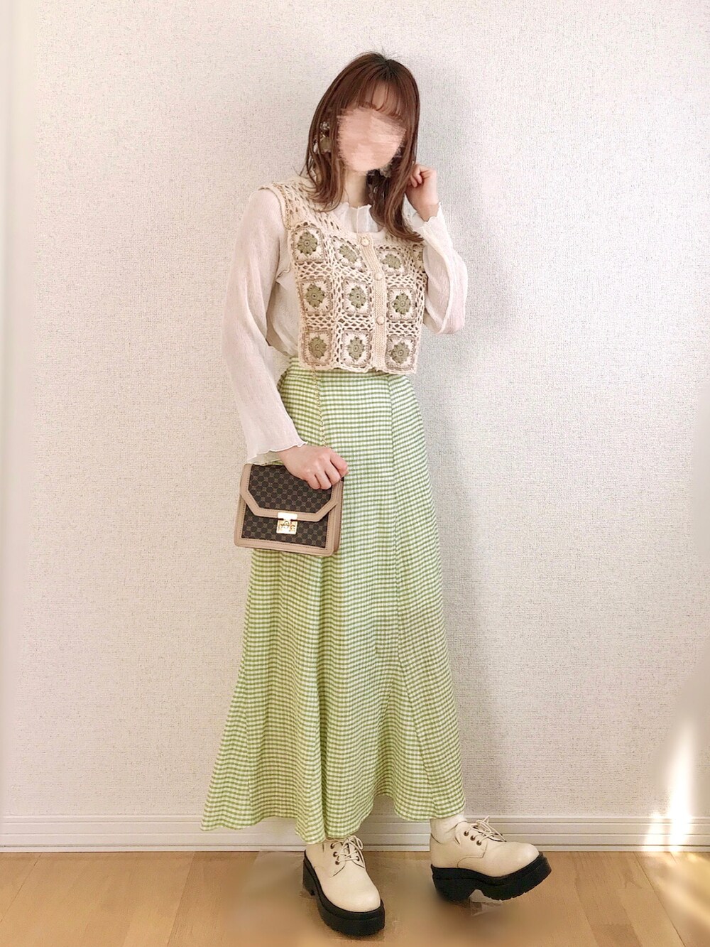 グリーン系のスカート、ホワイト系のベスト、ホワイト系のTシャツ/カットソーを着用したレディースの春コーディネートの2枚目の写真