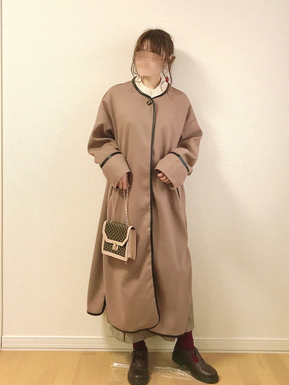 ブラウン系のノーカラーコート、ベージュ系のベスト、ブラウン系のスカートを着用したレディースの冬コーディネートの3枚目の写真