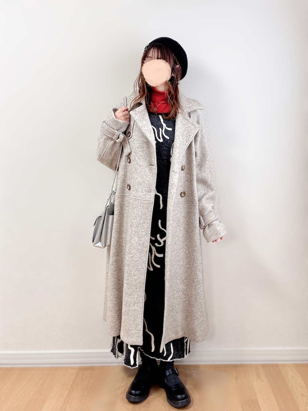 ベージュ系のチェスターコート、ブラック系のワンピース、オレンジ系のTシャツ/カットソーを着用したレディースの冬コーディネートの2枚目の写真