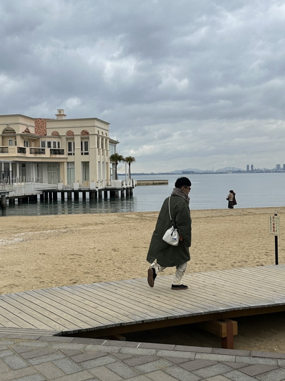 グリーン系のミリタリージャケット、ベージュ系のその他パンツ、ブラック系のスニーカーを着用したメンズの冬コーディネートの2枚目の写真