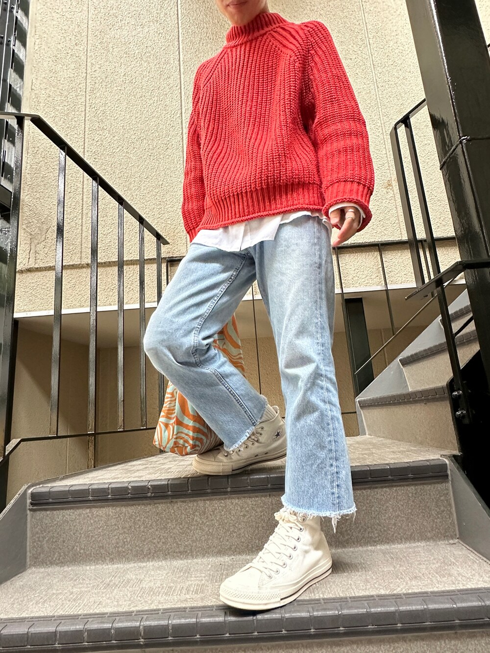 オレンジ系のニット/セーター、ブルー系のデニムパンツ、ホワイト系のスニーカーを着用したメンズの秋コーディネートの2枚目の写真