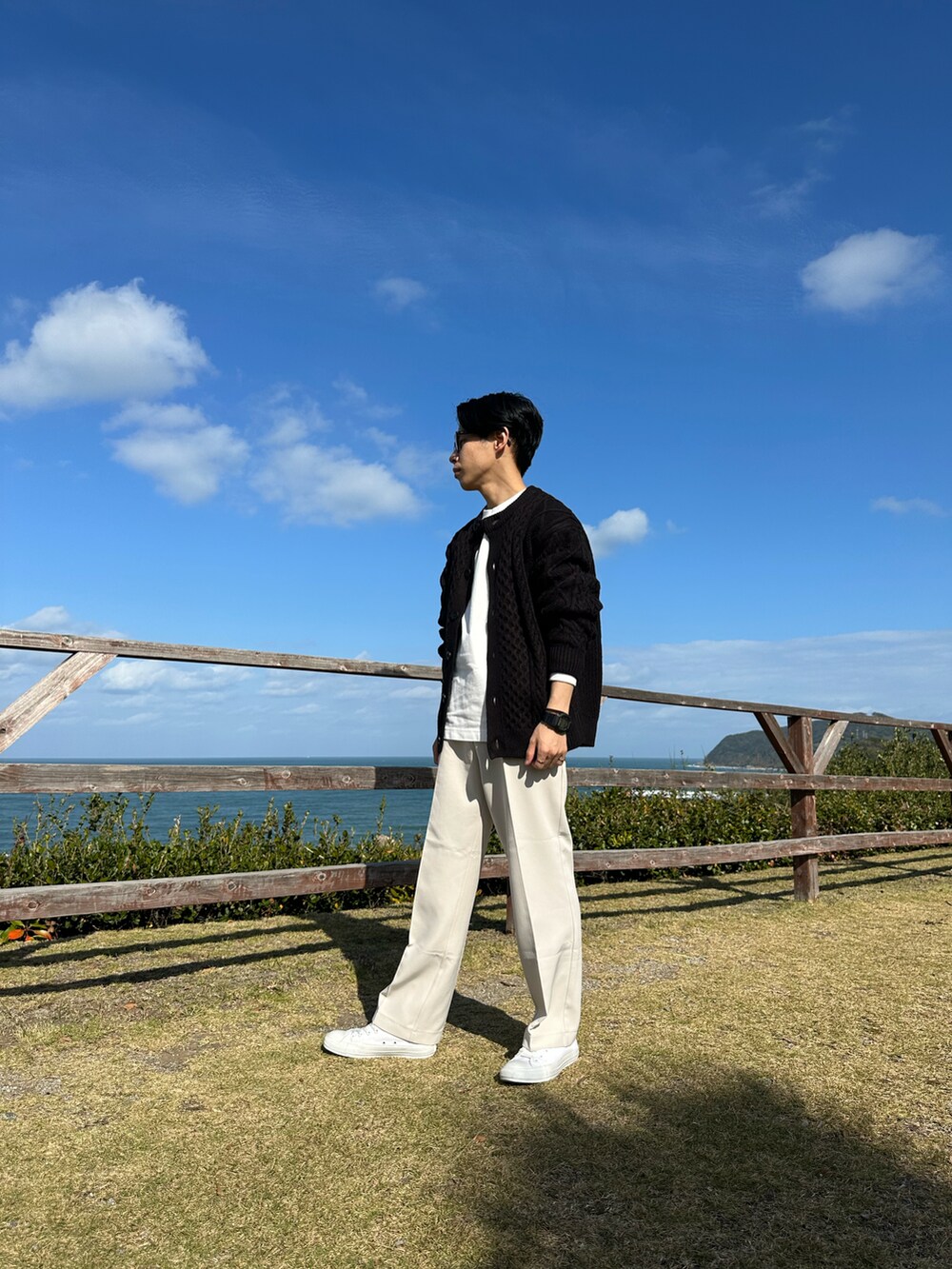 ブラック系のカーディガン/ボレロ、ホワイト系のスラックスを着用したメンズの秋コーディネートの2枚目の写真