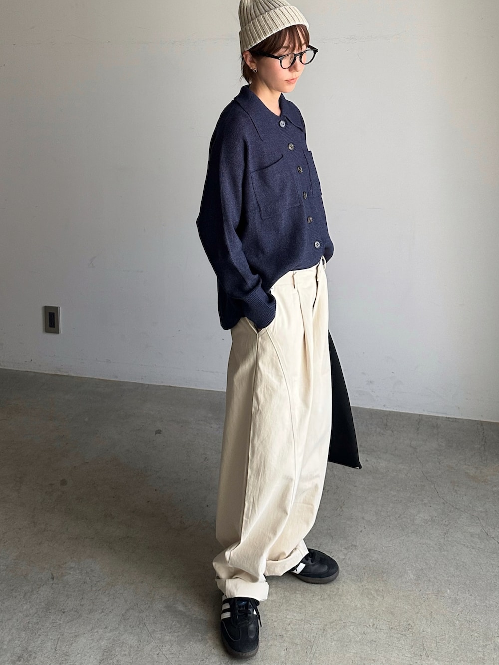 ブルー系のトップス、ブラック系のハンドバッグ、ブラック系のスニーカーを着用したレディースの秋コーディネートの2枚目の写真