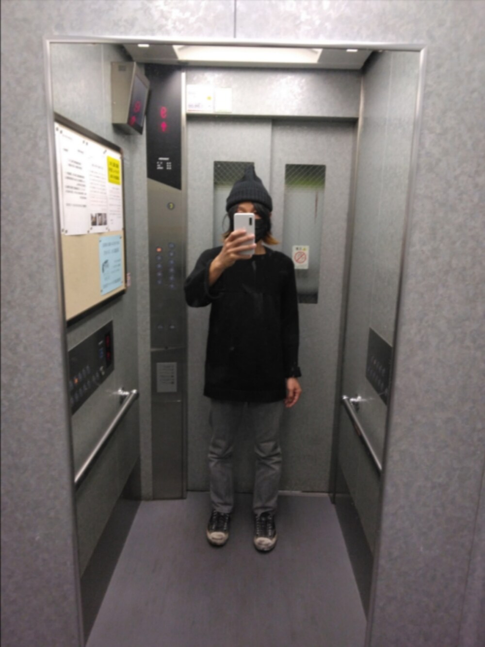 ブラック系のスニーカー、ブラック系のニット/セーター、グレー系のデニムパンツを着用したメンズの秋コーディネートの2枚目の写真