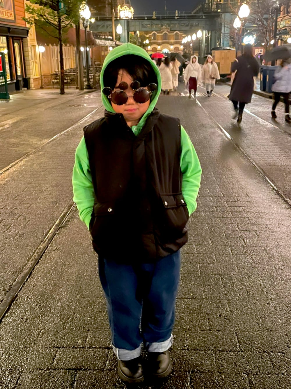 ブルー系のデニムパンツ、グリーン系のパーカー、ホワイト系のダウンベストを着用したキッズの冬コーディネートの2枚目の写真