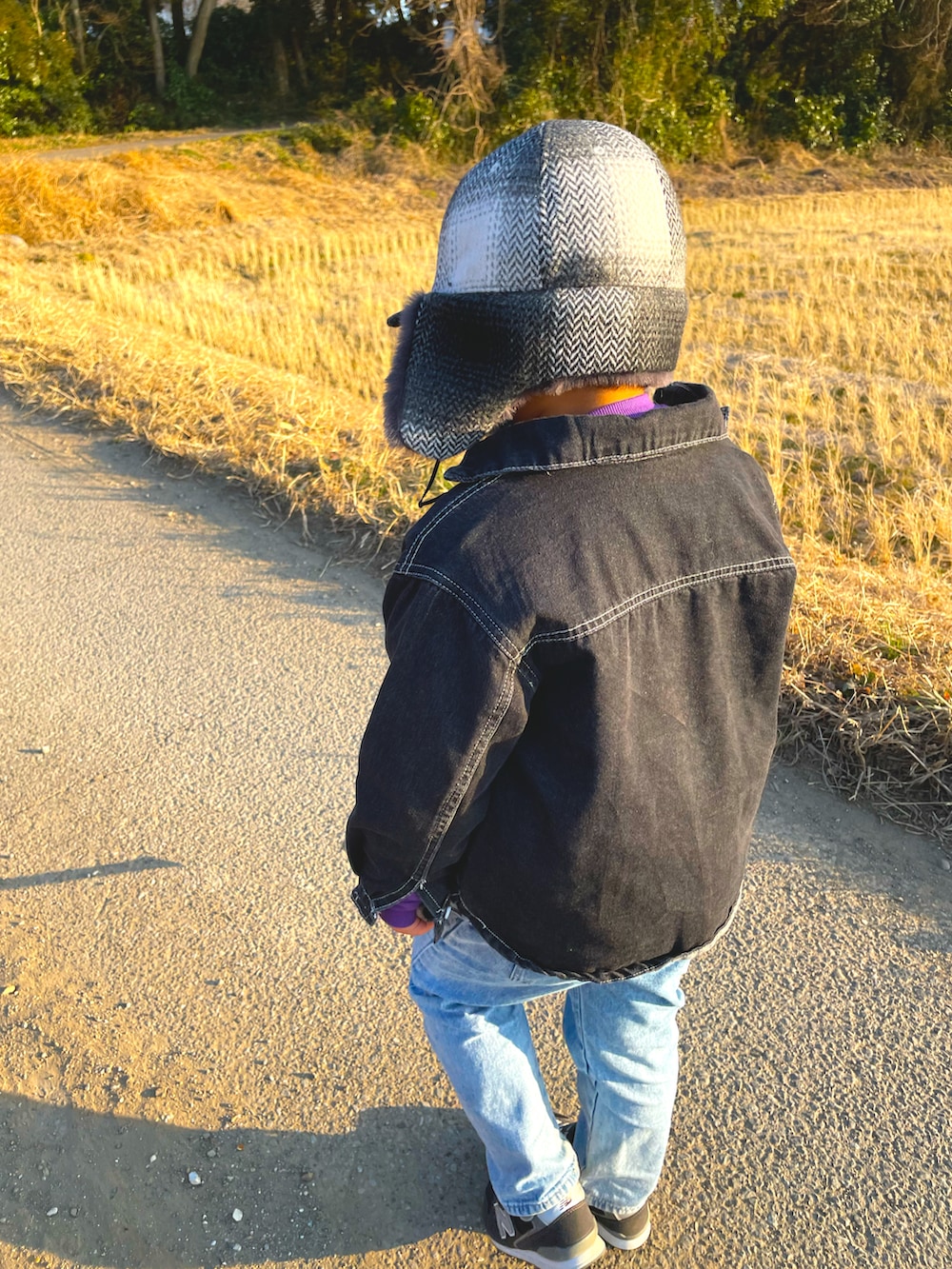 パープル系のスウェット、ブルー系のデニムパンツ、ブラック系のスニーカーを着用したキッズの冬コーディネートの2枚目の写真