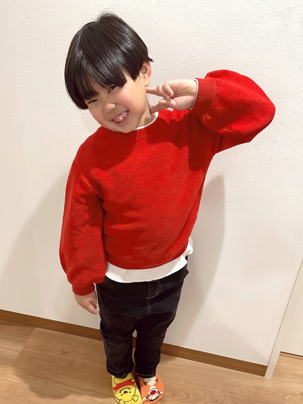 レッド系のニット/セーター、ブラック系のダッフルコート、ブラック系のデニムパンツを着用したキッズの冬コーディネートの3枚目の写真