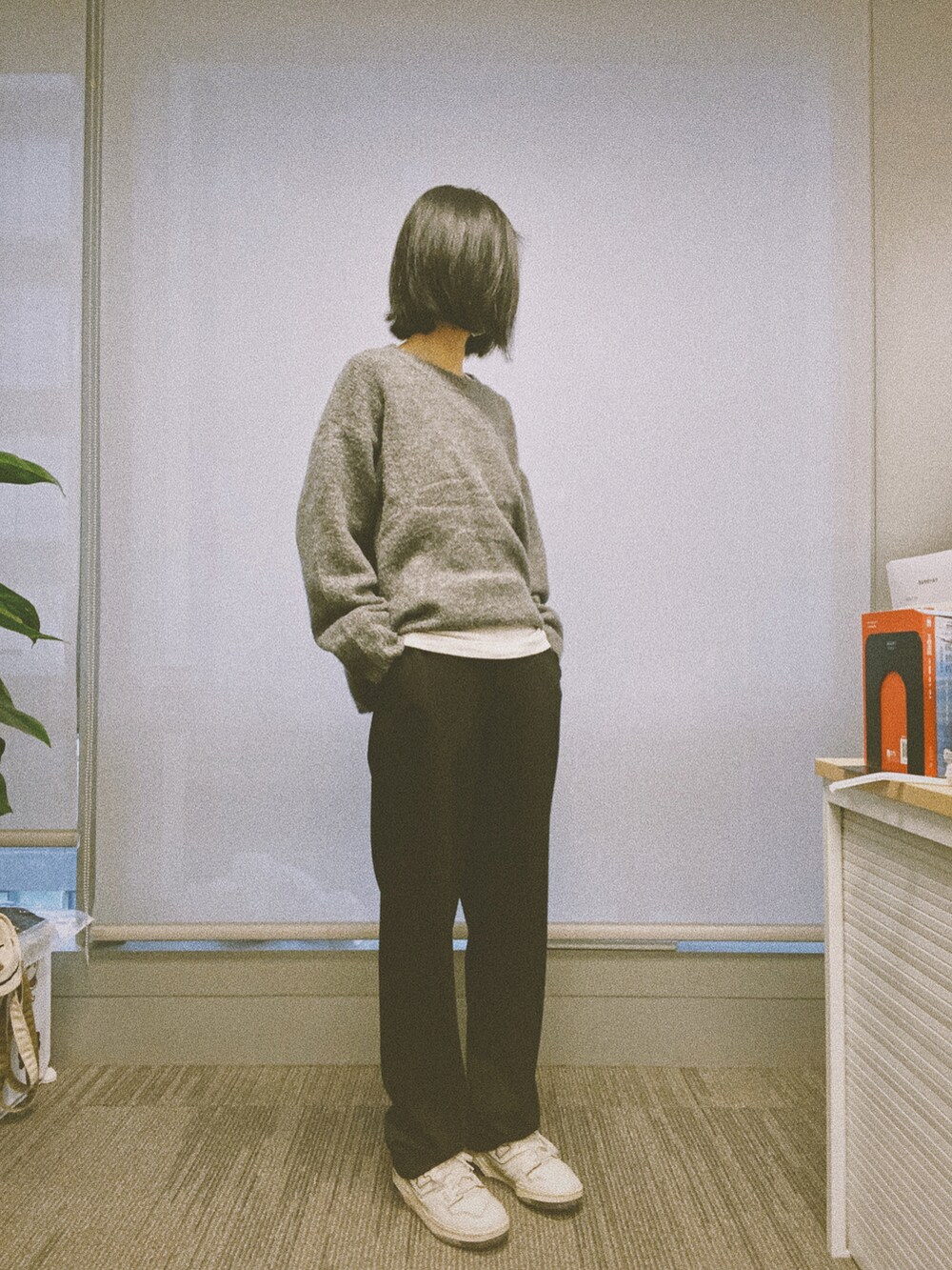 グレー系のニット/セーター、ホワイト系のタンクトップ、ブラック系のスラックスを着用したレディースの秋コーディネートの2枚目の写真