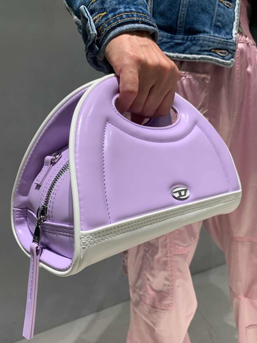 パープル系のハンドバッグ、ホワイト系のスニーカー、ブルー系のデニムジャケットを着用したレディースの夏コーディネートの2枚目の写真