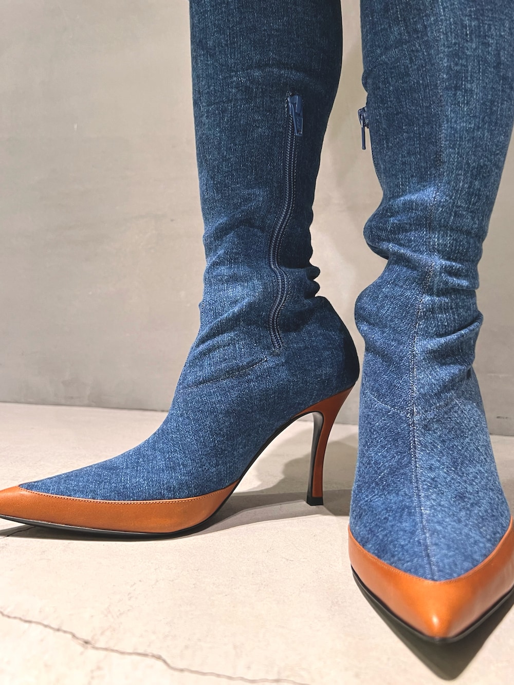 ブルー系のデニムスカート、ブルー系のニット/セーター、ホワイト系のショルダーバッグを着用したレディースの春コーディネートの4枚目の写真