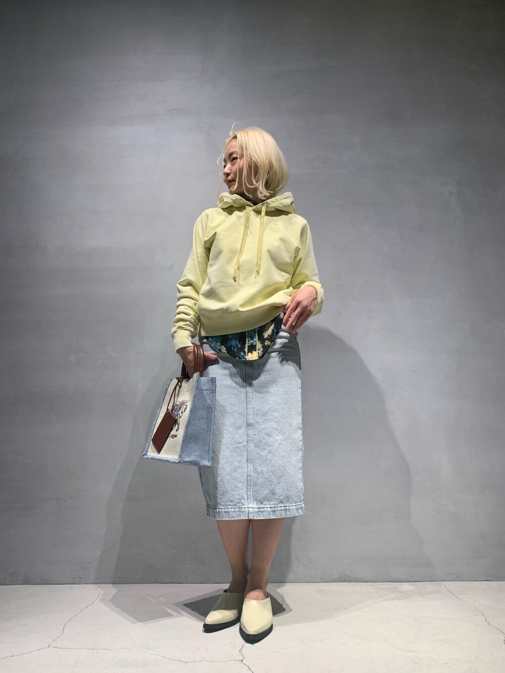 ホワイト系のトートバッグ、ブルー系のデニムスカート、ホワイト系のその他シューズを着用したレディースの春コーディネートの2枚目の写真