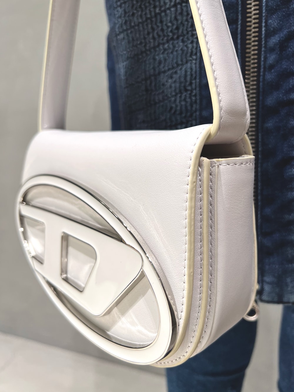 ブルー系のデニムスカート、ブルー系のニット/セーター、ホワイト系のショルダーバッグを着用したレディースの春コーディネートの3枚目の写真