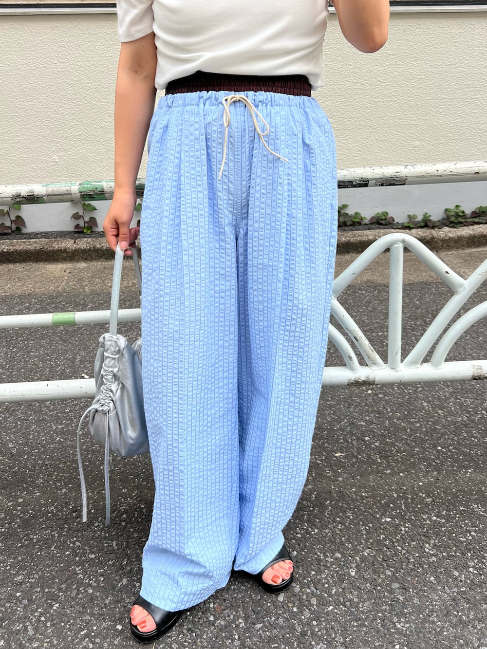 ホワイト系のTシャツ/カットソー、ブルー系のパンツ、シルバー系のショルダーバッグを着用したレディースの春コーディネートの3枚目の写真