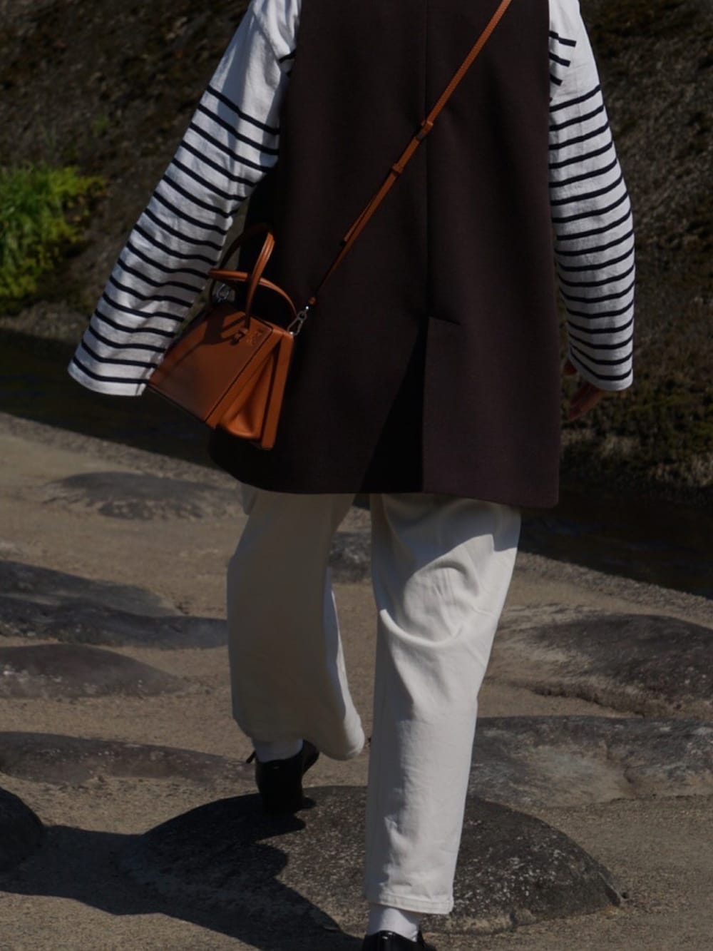ブラウン系のその他アウター、ホワイト系のその他パンツ、ブラウン系のショルダーバッグを着用したレディースの春コーディネートの2枚目の写真