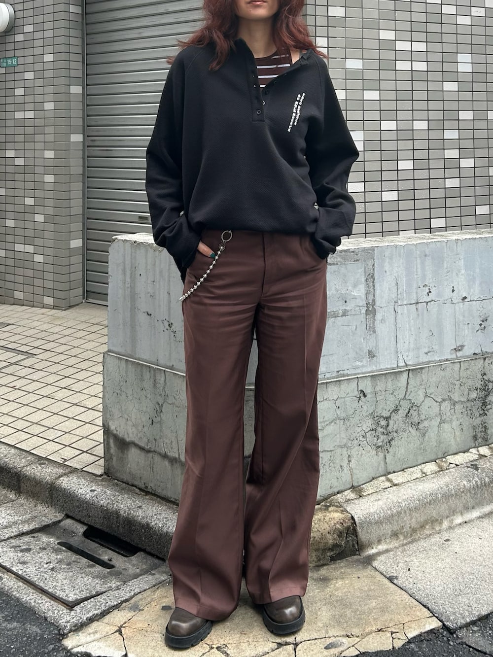 ブラック系のTシャツ/カットソー、ブラウン系のスラックス、ブラウン系のブーツを着用したレディースの春コーディネートの2枚目の写真