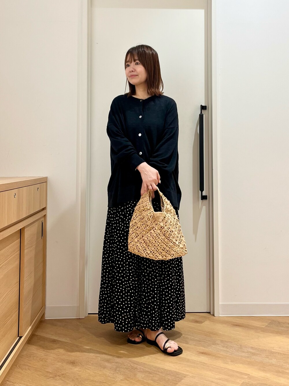 ブラック系のカーディガン/ボレロ、ベージュ系のハンドバッグ、ブラック系のサンダルを着用したレディースの夏コーディネートの3枚目の写真