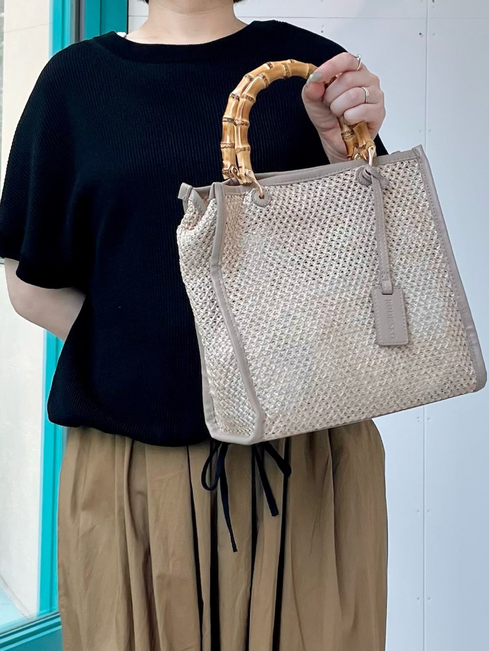 ブラック系のニット/セーター、ベージュ系のその他パンツ、ベージュ系のショルダーバッグを着用したレディースの夏コーディネートの6枚目の写真