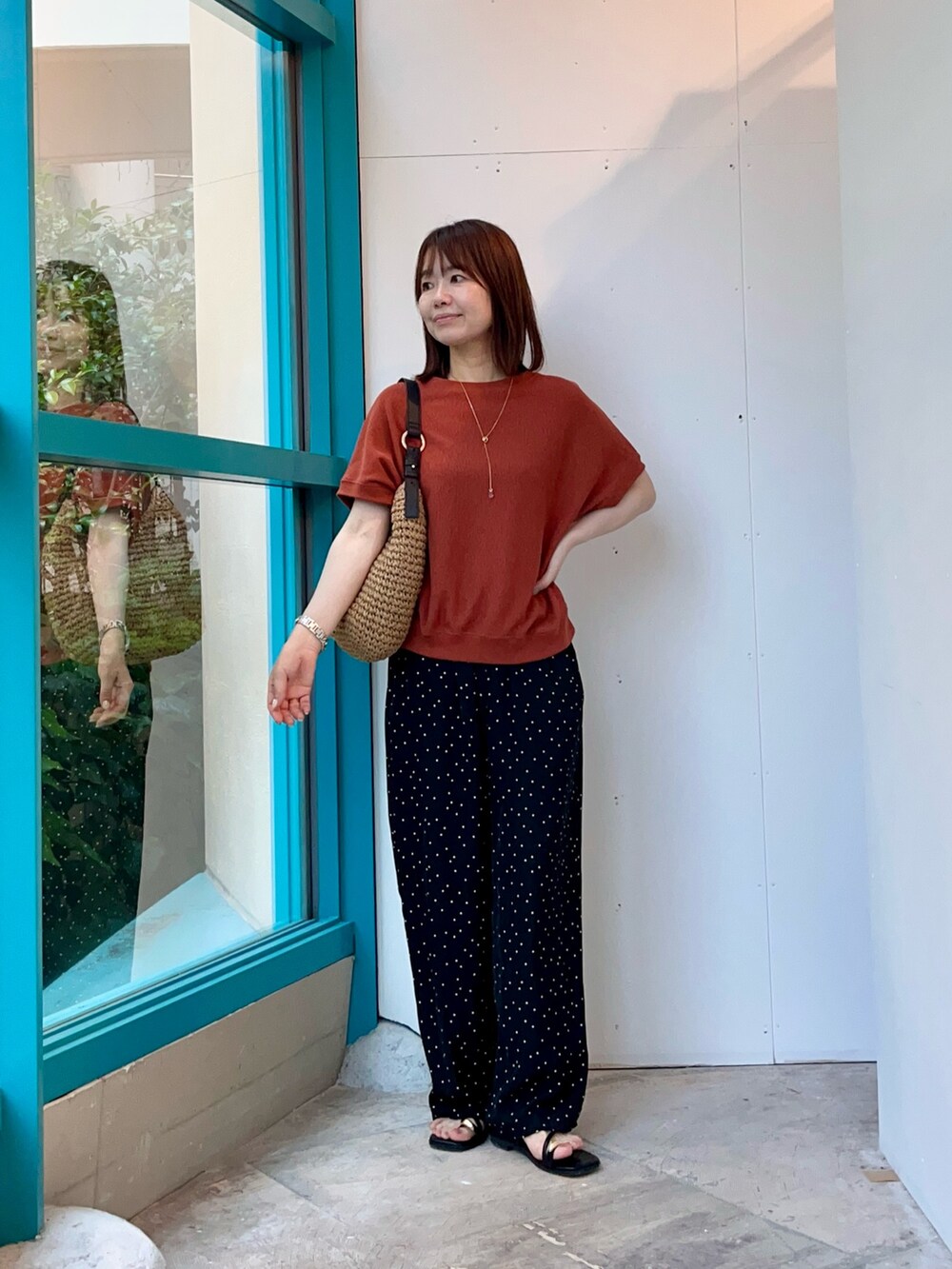 オレンジ系のTシャツ/カットソー、イエロー系のトートバッグ、ブラック系のその他パンツを着用したレディースの夏コーディネートの3枚目の写真