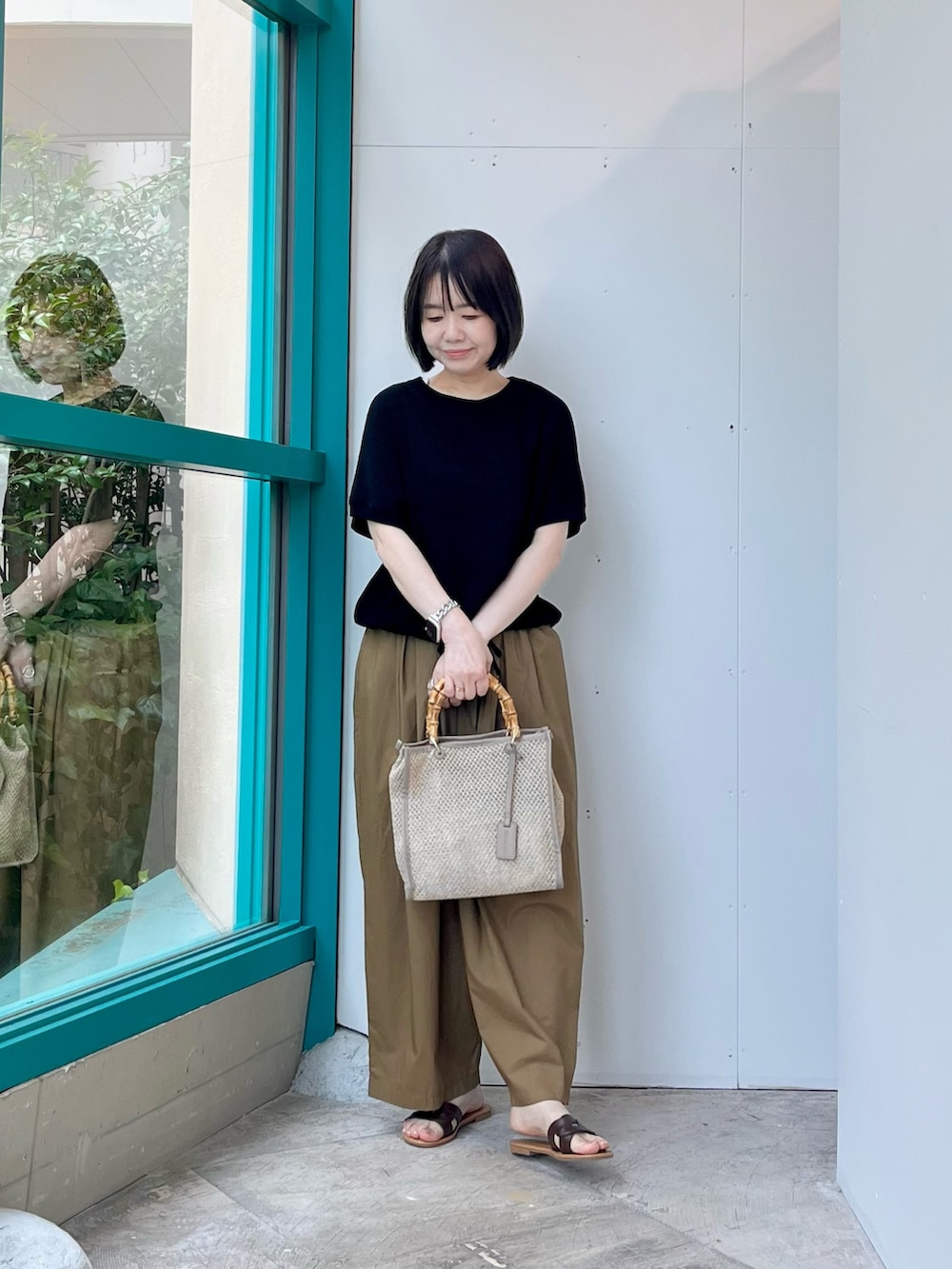 ブラック系のニット/セーター、ベージュ系のその他パンツ、ベージュ系のショルダーバッグを着用したレディースの夏コーディネートの4枚目の写真