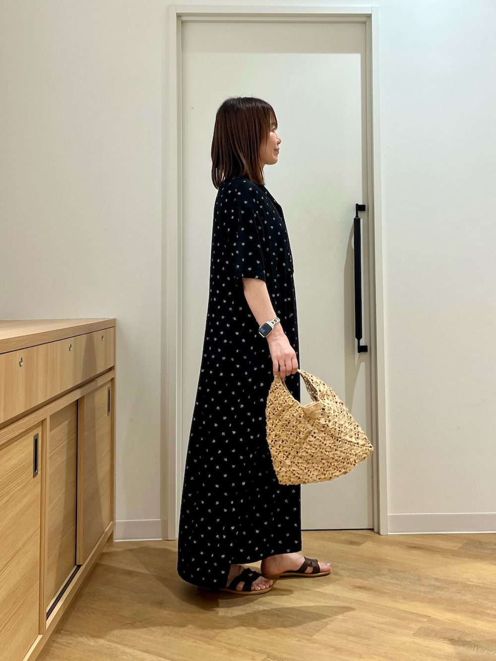 ブラック系のワンピース、ベージュ系のハンドバッグ、ブラウン系のサンダルを着用したレディースの夏コーディネートの2枚目の写真