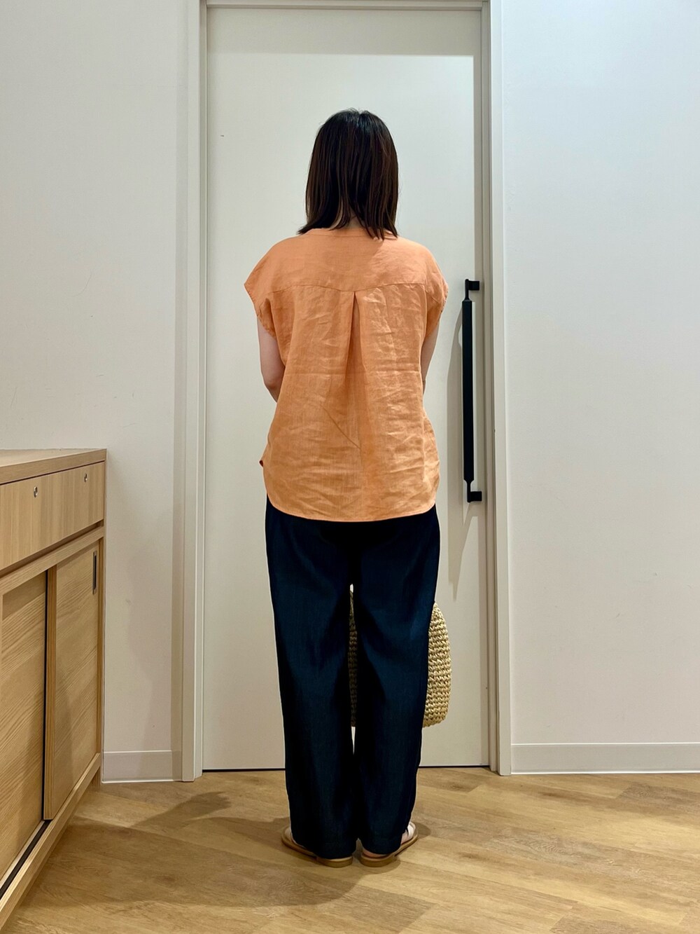 オレンジ系のシャツ/ブラウス、ベージュ系のトートバッグ、ブルー系のデニムパンツを着用したレディースの夏コーディネートの2枚目の写真