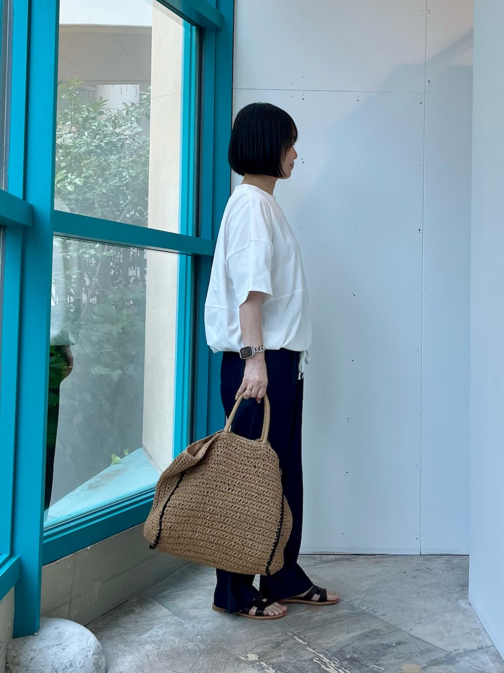 ホワイト系のTシャツ/カットソー、ブルー系のデニムパンツ、ベージュ系のトートバッグを着用したレディースの夏コーディネートの2枚目の写真