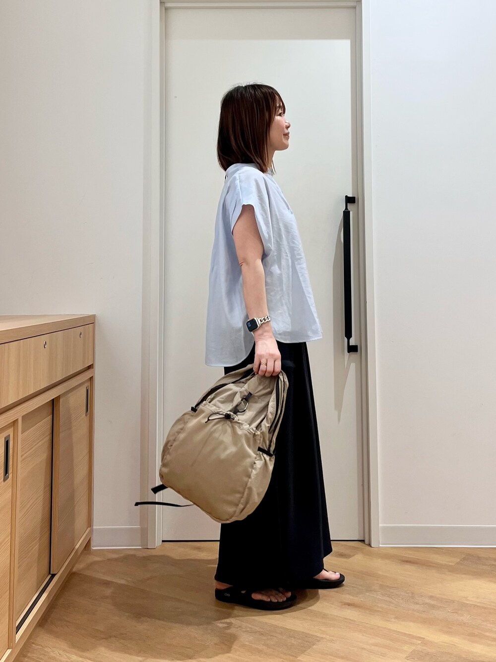 ホワイト系のタンクトップ、ブルー系のシャツ/ブラウス、ベージュ系のバックパック/リュックを着用したレディースの夏コーディネートの2枚目の写真