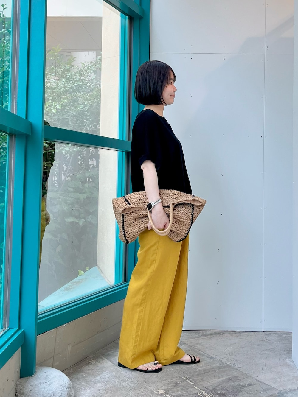 ブラック系のニット/セーター、イエロー系のその他パンツ、ベージュ系のトートバッグを着用したレディースの夏コーディネートの2枚目の写真