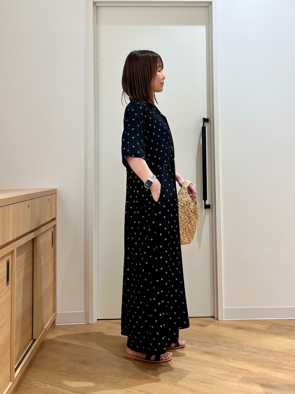 ブラック系のワンピース、ベージュ系のハンドバッグ、ブラウン系のサンダルを着用したレディースの夏コーディネートの4枚目の写真