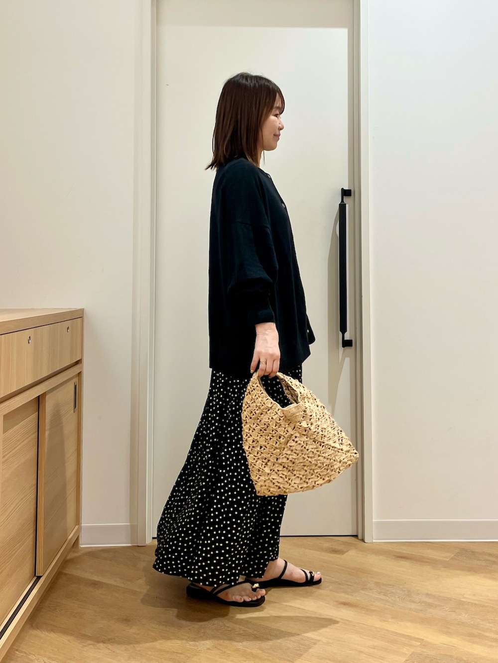 ブラック系のカーディガン/ボレロ、ベージュ系のハンドバッグ、ブラック系のサンダルを着用したレディースの夏コーディネートの2枚目の写真