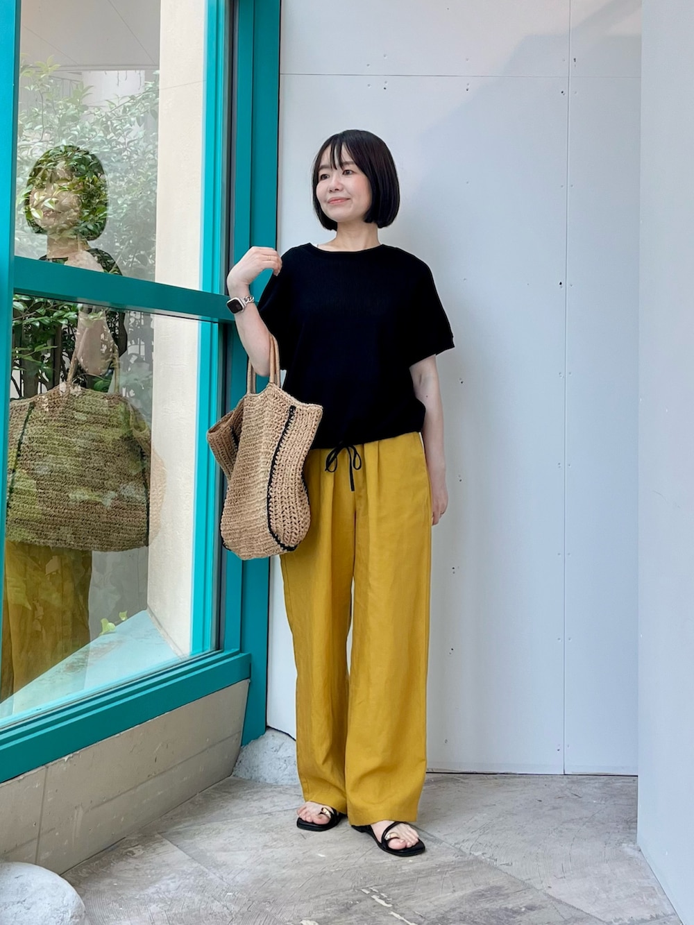 ブラック系のニット/セーター、イエロー系のその他パンツ、ベージュ系のトートバッグを着用したレディースの夏コーディネートの3枚目の写真