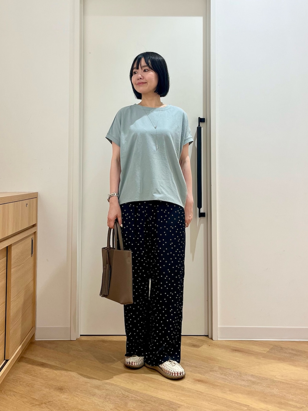 グレー系のトートバッグ、グリーン系のTシャツ/カットソー、ブルー系のその他パンツを着用したレディースの夏コーディネートの2枚目の写真