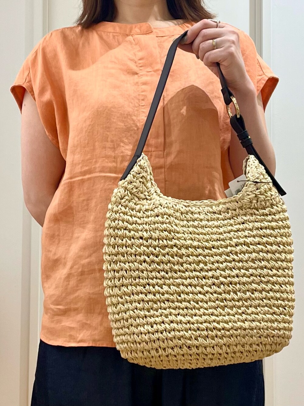 オレンジ系のシャツ/ブラウス、ベージュ系のトートバッグ、ブルー系のデニムパンツを着用したレディースの夏コーディネートの3枚目の写真