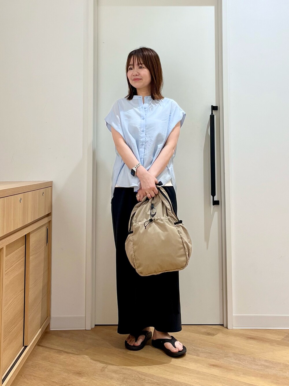 ホワイト系のタンクトップ、ブルー系のシャツ/ブラウス、ベージュ系のバックパック/リュックを着用したレディースの夏コーディネートの3枚目の写真