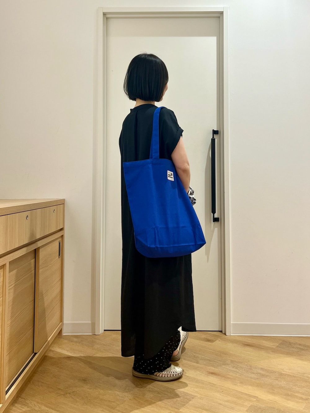 ブラック系のワンピース、ブルー系のトートバッグ、ブルー系のその他パンツを着用したレディースの夏コーディネートの2枚目の写真