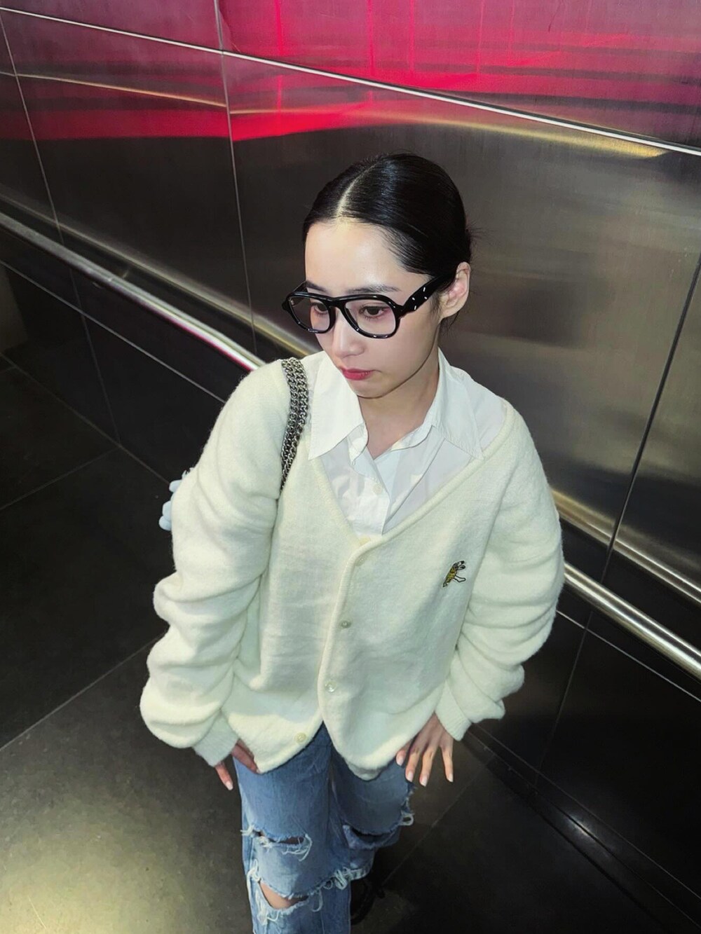 ホワイト系のカーディガン/ボレロ、ホワイト系のシャツ/ブラウス、ブラック系のメガネを着用したレディースの春コーディネートの2枚目の写真