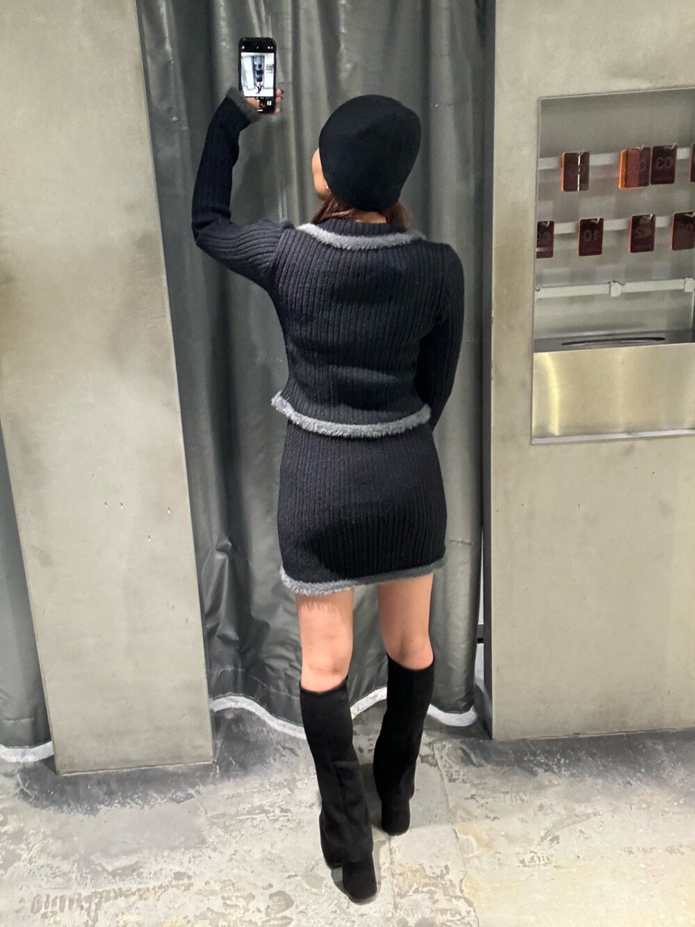 ブラック系のニット/セーター、ブラック系のスカート、ブラック系のブーツを着用したレディースの秋コーディネートの3枚目の写真