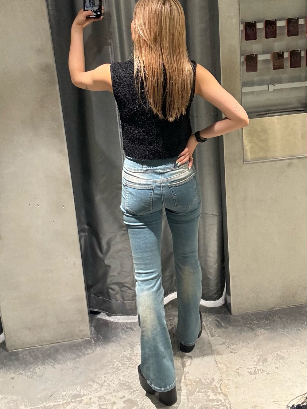 ブラック系のタンクトップ、ブルー系のデニムパンツ、ブラック系のサンダルを着用したレディースの夏コーディネートの3枚目の写真