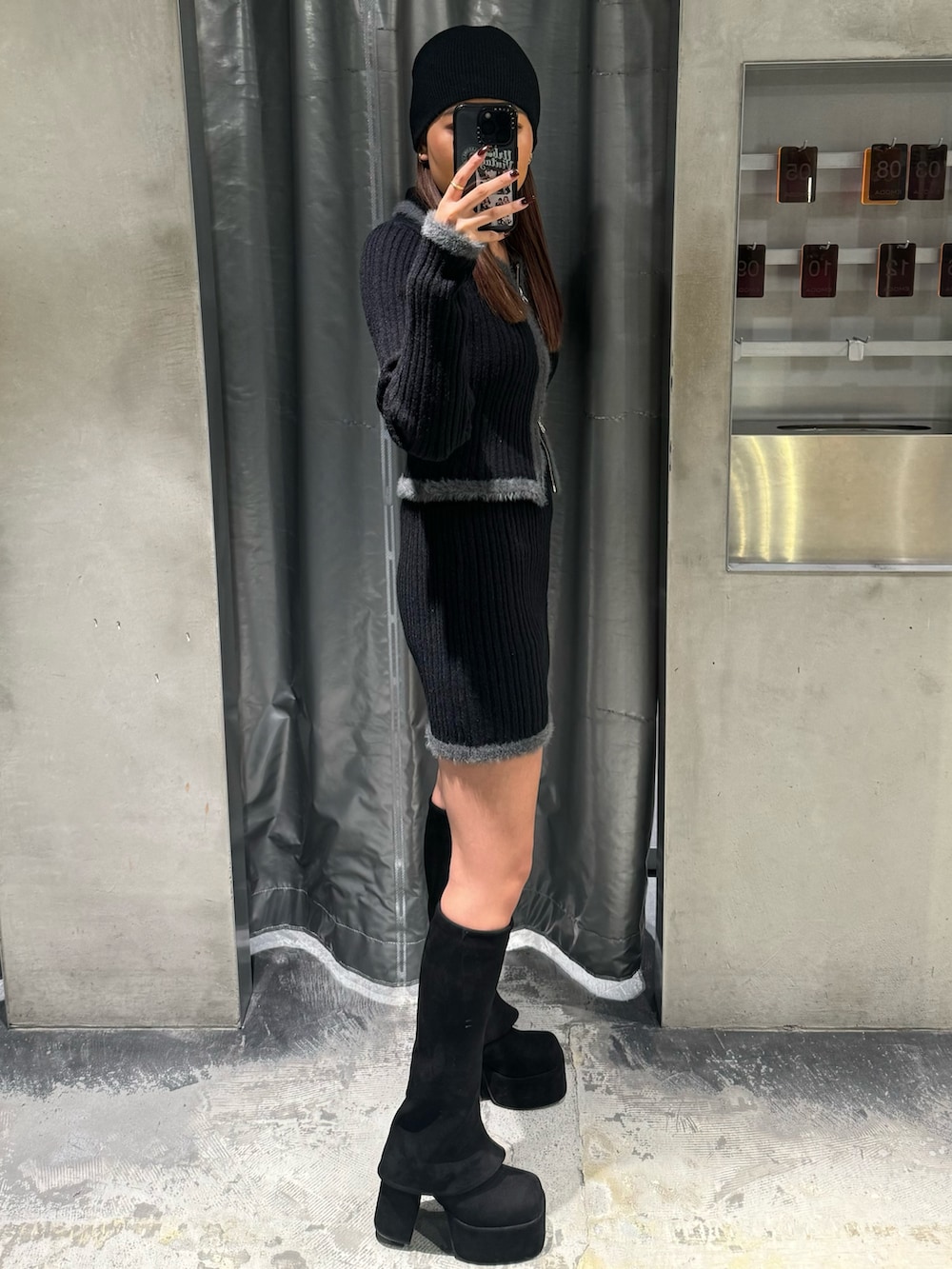 ブラック系のニット/セーター、ブラック系のスカート、ブラック系のブーツを着用したレディースの秋コーディネートの2枚目の写真