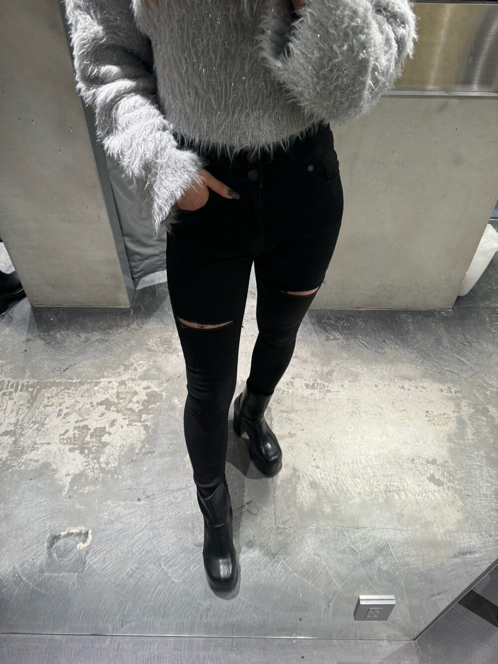 グレー系のニット/セーター、ブラック系のデニムパンツ、ブラック系のブーツを着用したレディースの冬コーディネートの2枚目の写真