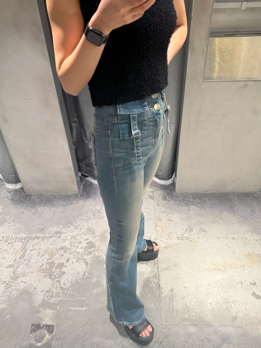 ブラック系のタンクトップ、ブルー系のデニムパンツ、ブラック系のサンダルを着用したレディースの夏コーディネートの7枚目の写真