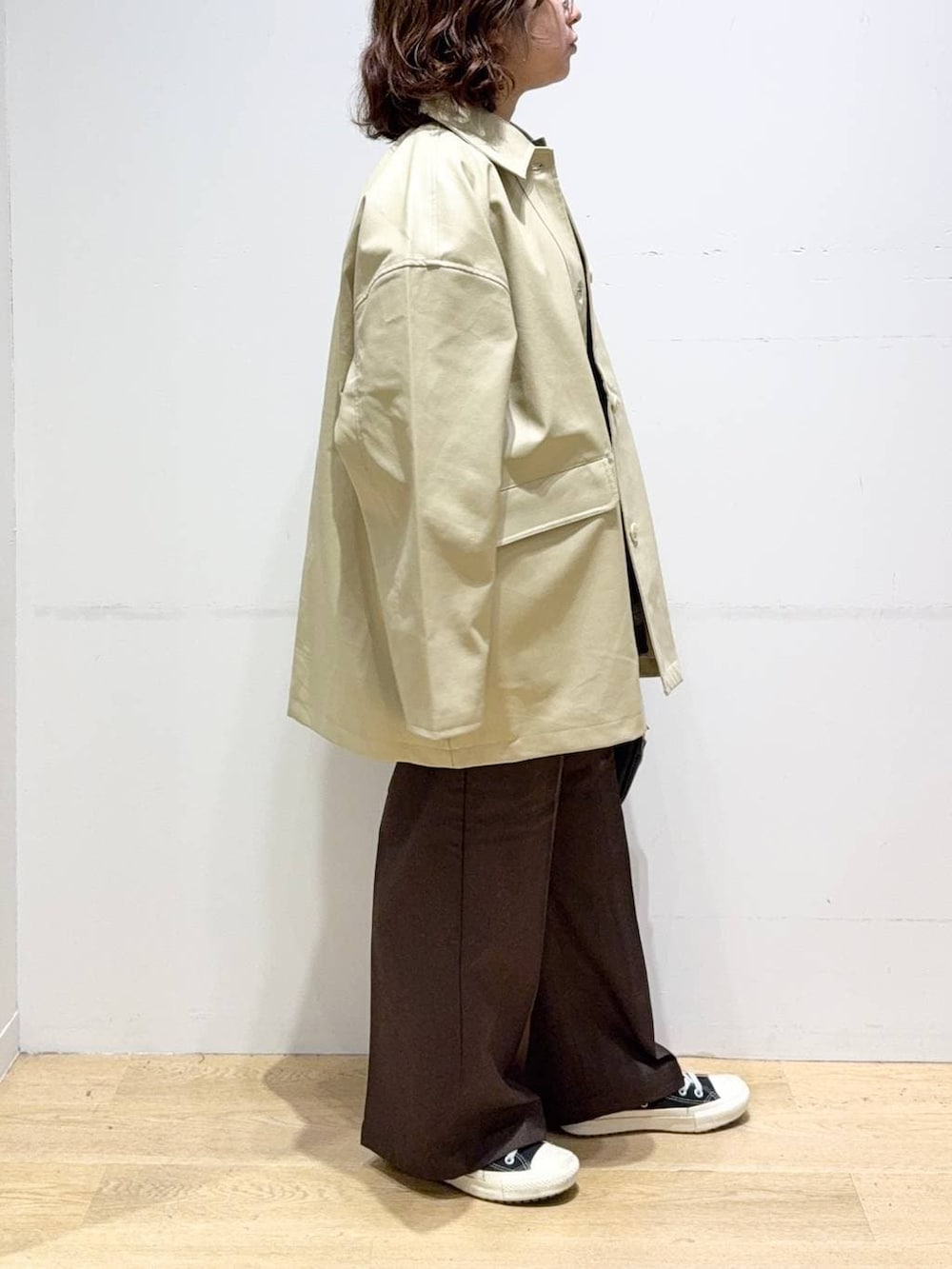 ベージュ系のステンカラーコート、ブラウン系のスラックス、グリーン系のシャツ/ブラウスを着用したレディースの秋コーディネートの3枚目の写真